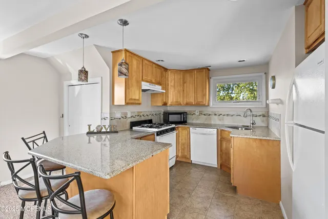 a kitchen with granite countertop a sink cabinets stainless steel appliances and a window