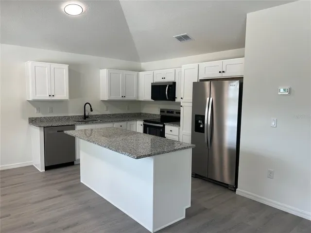 a kitchen with stainless steel appliances granite countertop a refrigerator a sink a stove a microwave and island