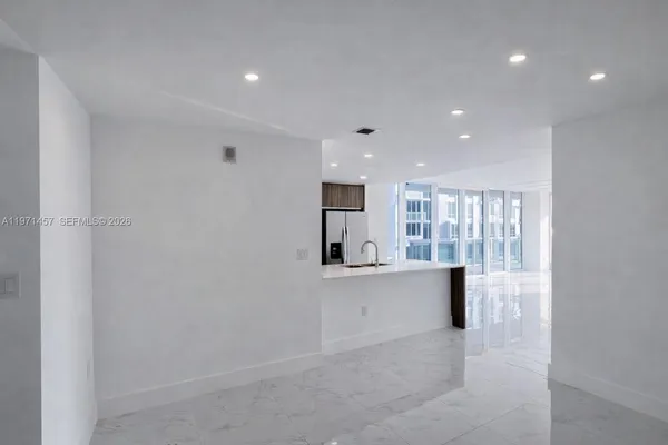 a large white kitchen with kitchen island a sink stainless steel appliances and cabinets