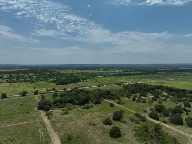 a view of a field with an ocean and trees