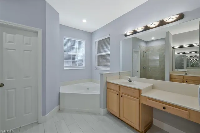 a bathroom with a sink double vanity granite tub shower and a mirror