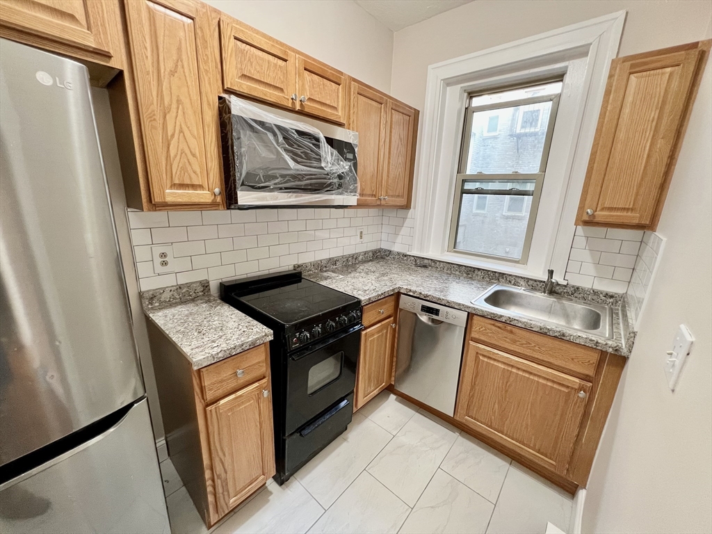 1669 Commonwealth Avenue, Unit 3 Boston, MA 02135 - Photo 3 of 10 a kitchen with granite countertop a sink stove and cabinets