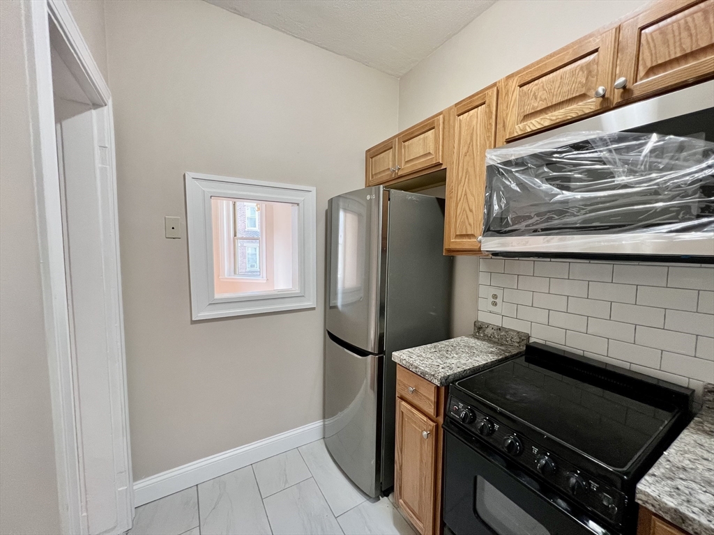 1669 Commonwealth Avenue, Unit 3 Boston, MA 02135 - Photo 4 of 10 a kitchen with a stove and a refrigerator