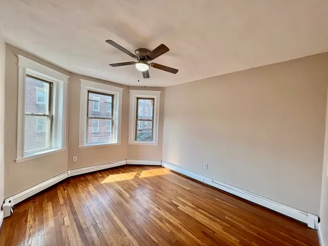 a view of empty room with wooden floor and fan