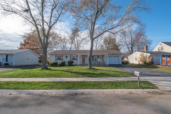 a front view of a house with a yard and a large tree