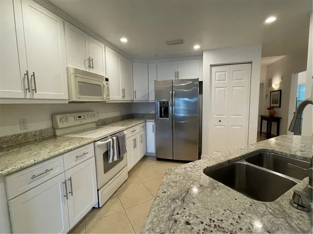 a kitchen with stainless steel appliances granite countertop a sink a stove a refrigerator and cabinets