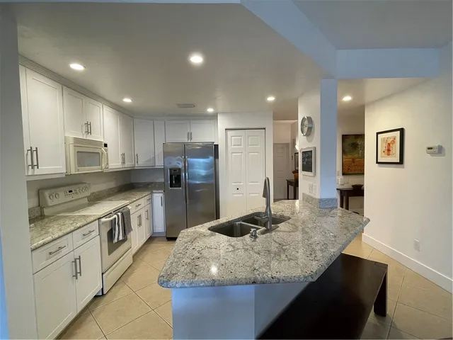 a kitchen with stainless steel appliances granite countertop a sink refrigerator and cabinets