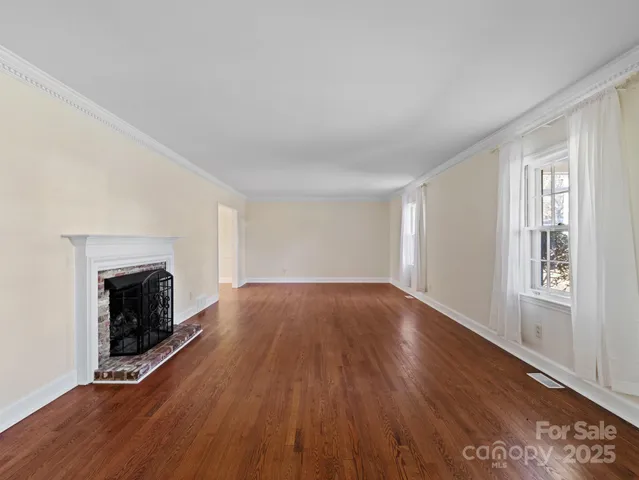 an empty room with wooden floor fireplace and windows