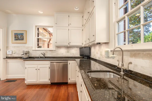 a kitchen with a sink wooden floor and white cabinets