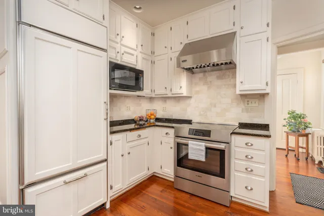 a kitchen with stainless steel appliances white cabinets and a wooden floor