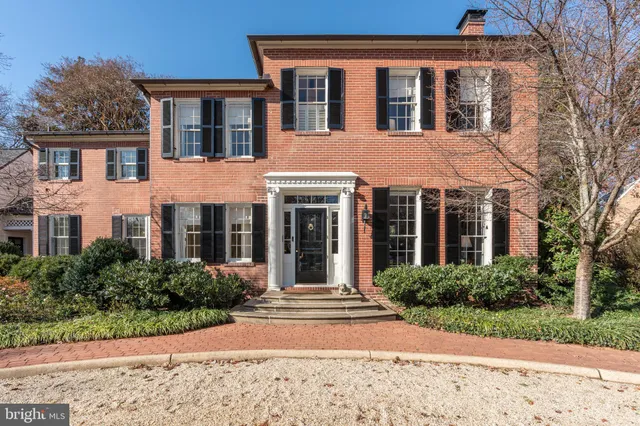 a view of a brick house with large windows and plants