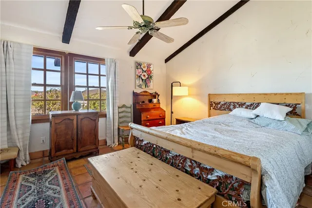 a bedroom with a bed next to a window with chair and table