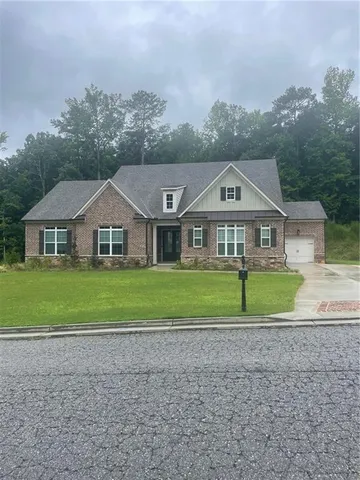 a front view of a house with a yard and large trees
