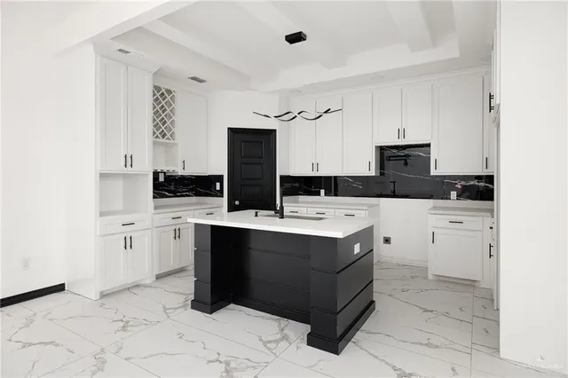 a kitchen with kitchen island granite countertop a sink a counter top space and cabinets