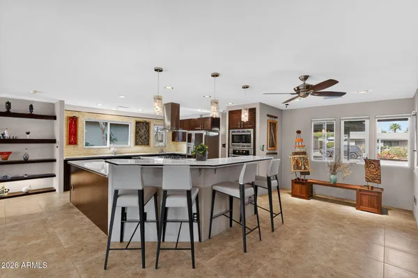 a open kitchen with stainless steel appliances kitchen island granite countertop a table and chairs in it