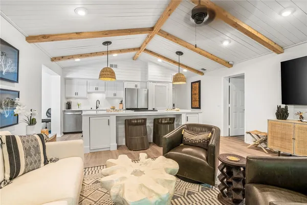 a living room with furniture a flat screen tv and kitchen view