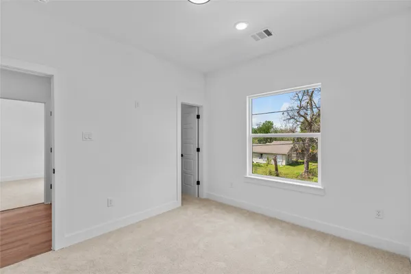 an empty room that has a window and painting on the wall