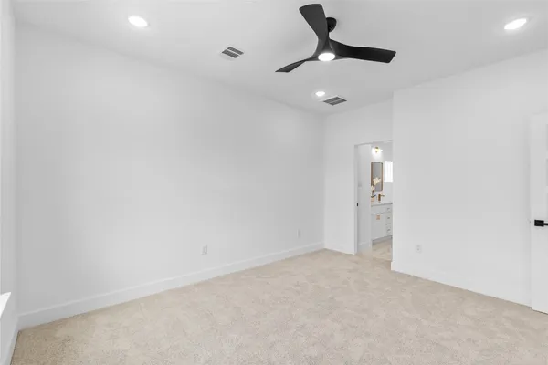 an empty room with a ceiling fan and carpet