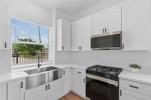 a kitchen with stainless steel appliances white cabinets and a stove top oven