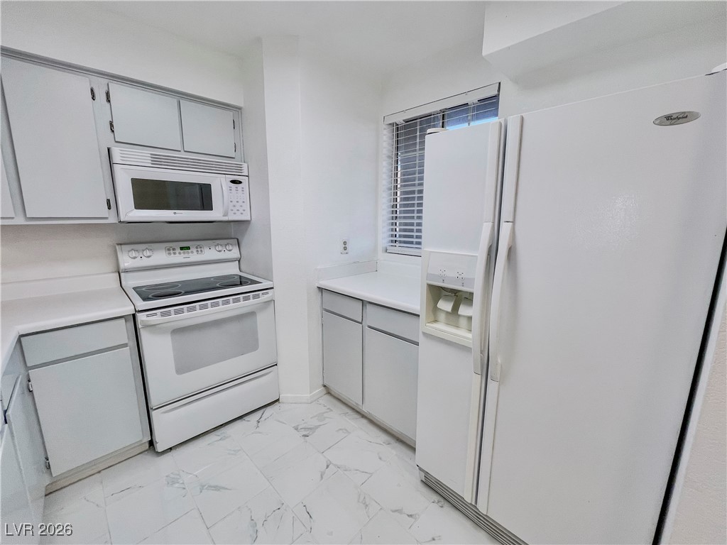 2044 Mesquite Lane, Unit 202 Laughlin, NV 89029 - Photo 4 of 47 Kitchen with light countertops, white appliances, marble finish floor, and gray cabinets