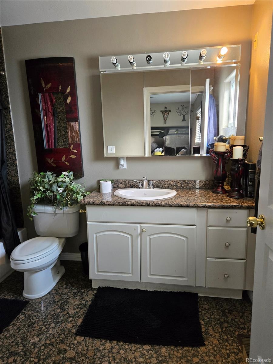 633 South Stuart Street Denver, CO 80219 - Photo 16 of 28 a bathroom with a granite countertop toilet sink and mirror