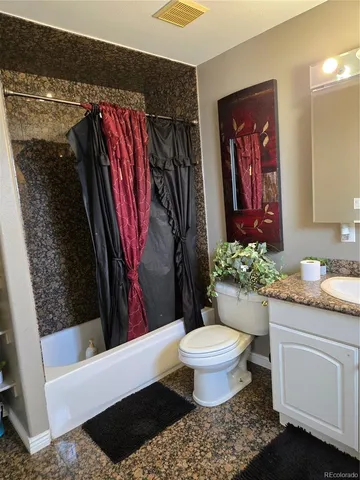 a bathroom with a granite countertop sink and a toilet
