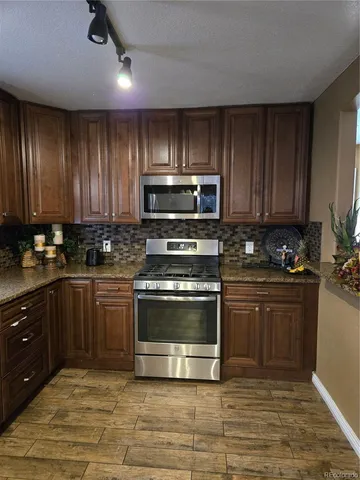 a kitchen with stainless steel appliances granite countertop a stove a sink and a microwave