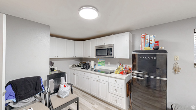 630 1100 West Provo, UT 84601 - Photo 28 of 64 Kitchen featuring white cabinetry, light-toned countertops, wood-finish flooring, and a stainless steel microwave