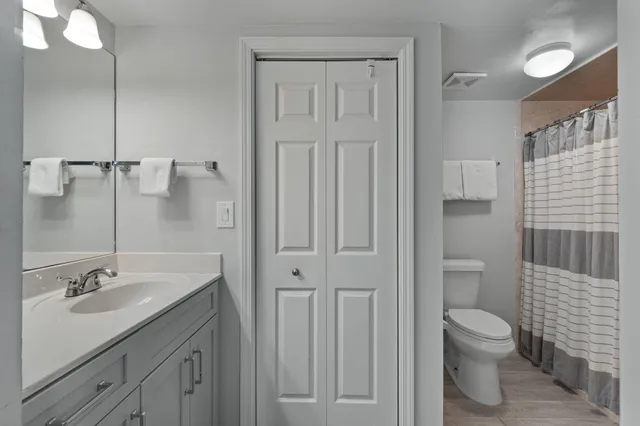 a bathroom with a granite countertop sink a toilet and a shower