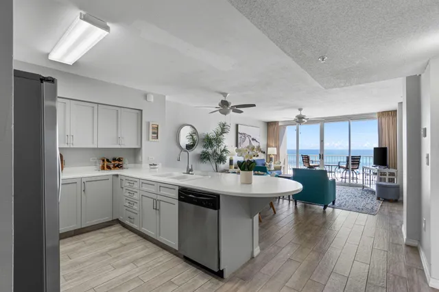 a view of a kitchen counter top space with sink wooden floor and view living room