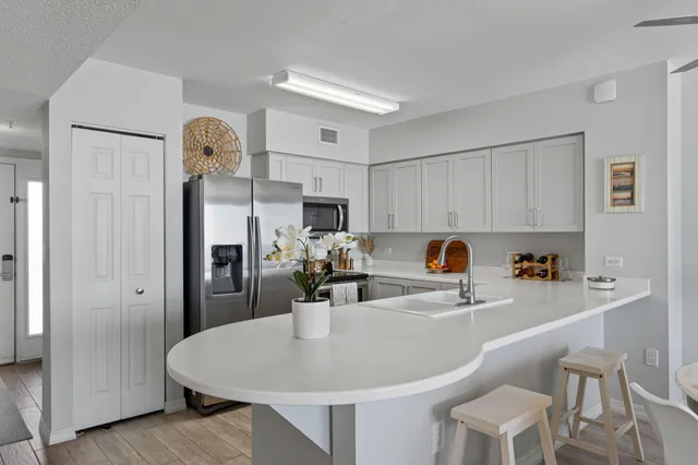 a kitchen with stainless steel appliances a white refrigerator a sink dishwasher and white cabinets with wooden floor