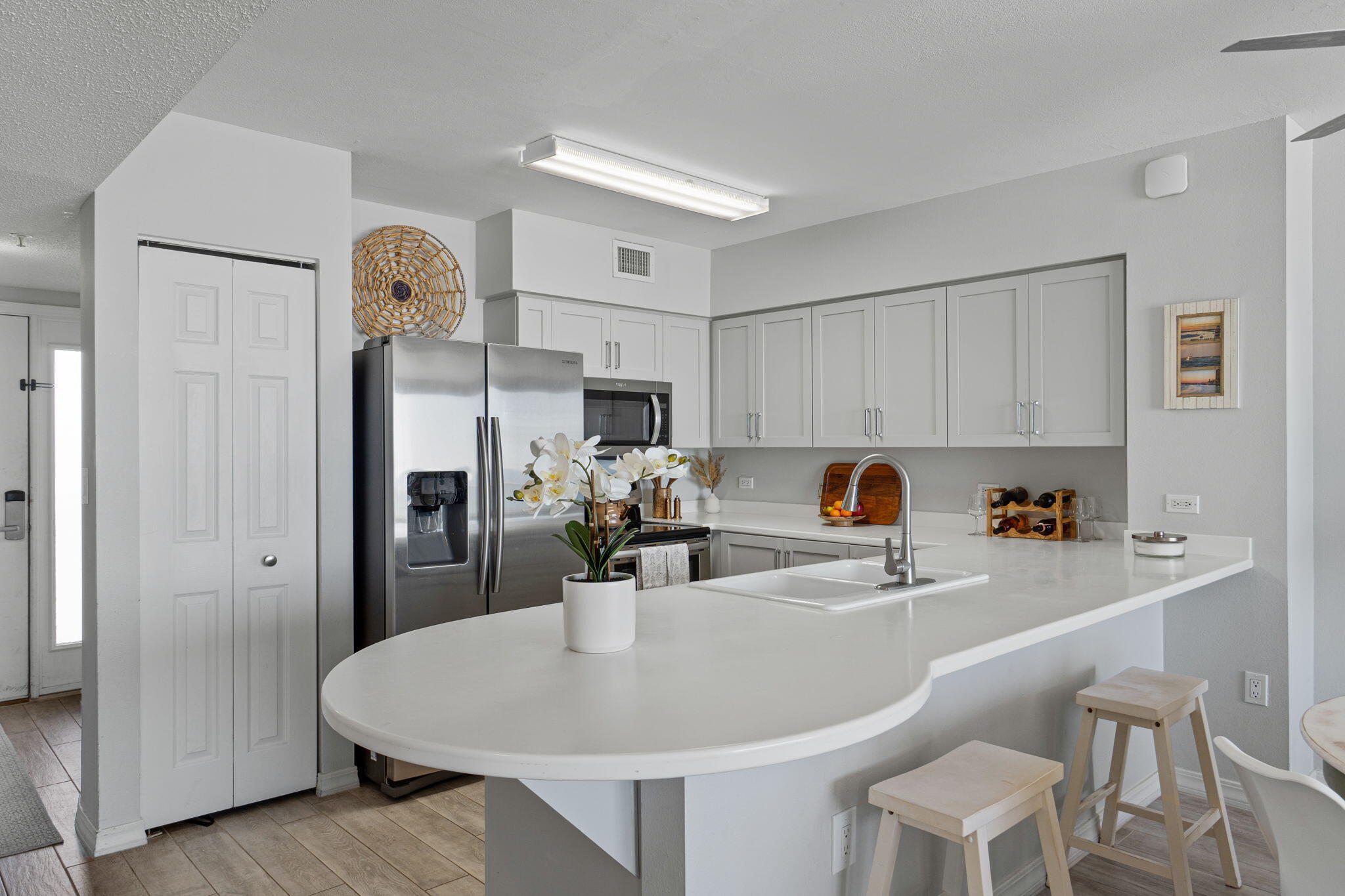 520 Santa Rosa Boulevard, Unit 404 Fort Walton Beach, FL 32548 - Photo 8 of 44 a kitchen with stainless steel appliances a white refrigerator a sink dishwasher and white cabinets with wooden floor