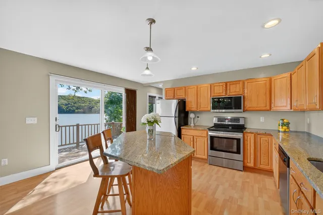 a kitchen with stainless steel appliances granite countertop a kitchen island hardwood floor sink stove dining table and chairs