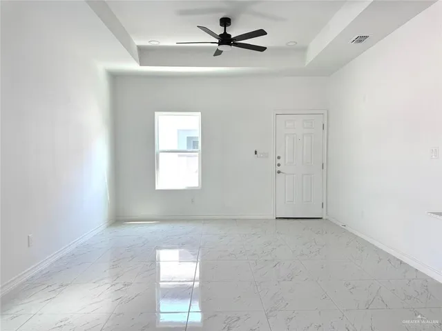 an empty room with windows and fan