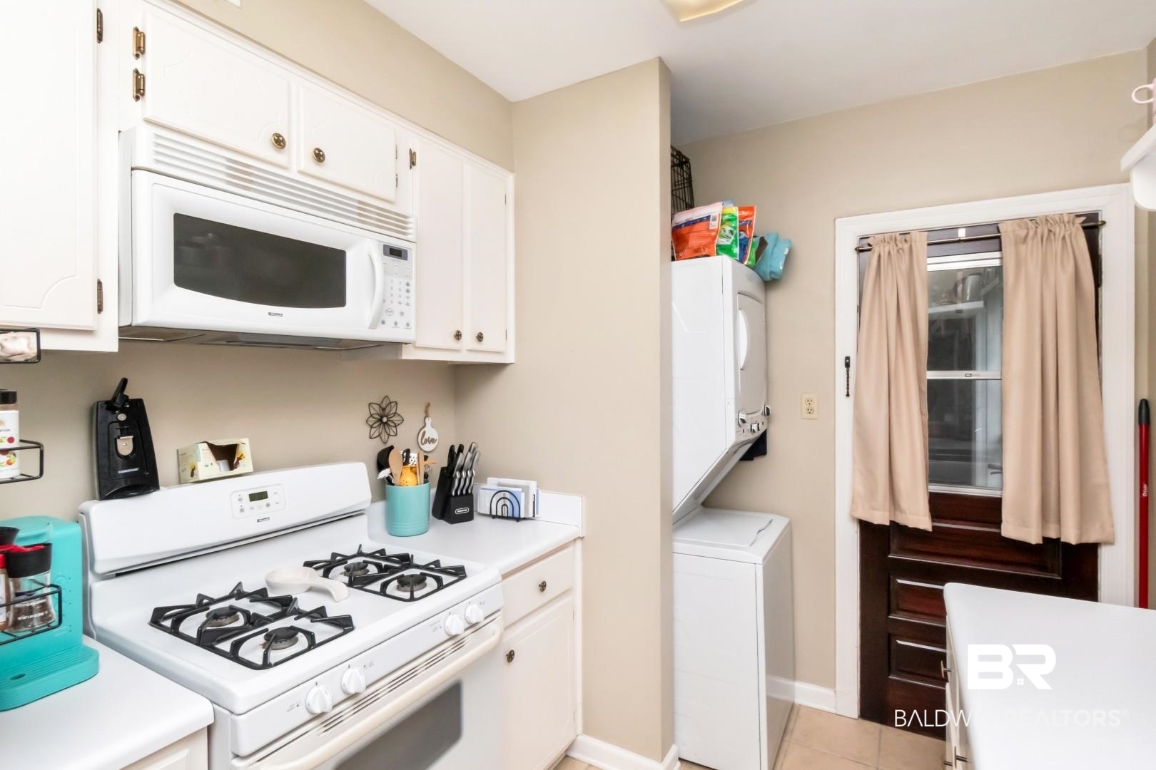 214 Upham Street, Unit 17C Mobile, AL 36607 - Photo 21 of 32 Kitchen featuring white appliances, light countertops, white cabinetry, and stacked washer / drying machine