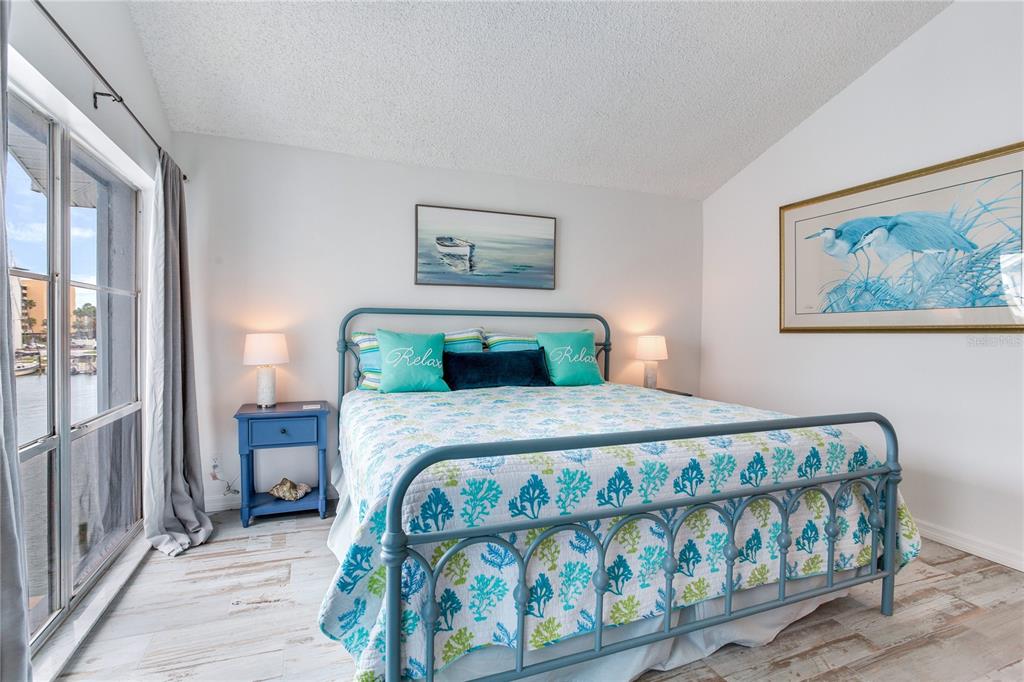 171 Medallion Boulevard, Unit H Madeira Beach, FL 33708 - Photo 20 of 44 a bedroom with a bed and a painting on the wall