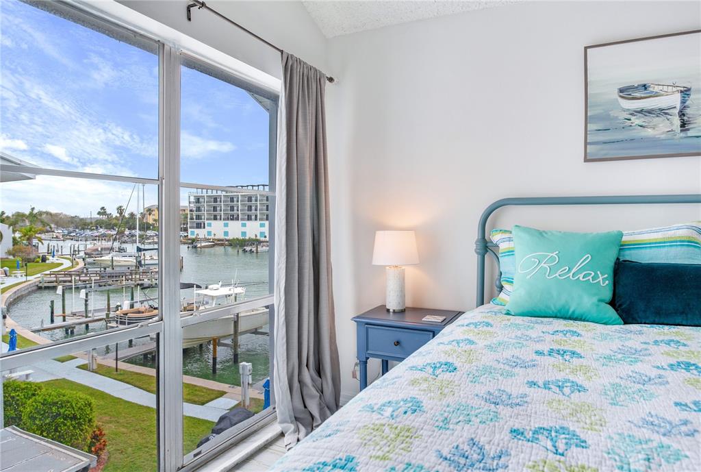 171 Medallion Boulevard, Unit H Madeira Beach, FL 33708 - Photo 22 of 44 a bedroom with a bed and a view of balcony