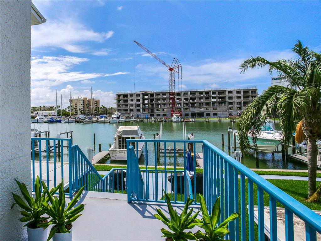 171 Medallion Boulevard, Unit H Madeira Beach, FL 33708 - Photo 36 of 44 a view of a balcony with wooden chairs and floor to ceiling window
