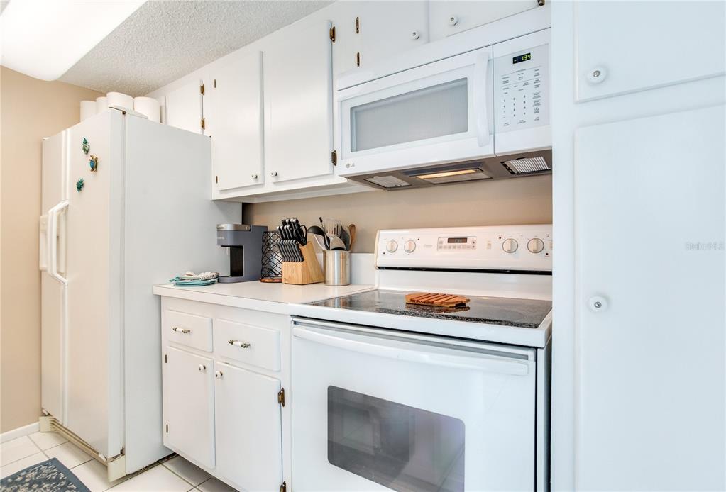 171 Medallion Boulevard, Unit H Madeira Beach, FL 33708 - Photo 9 of 44 a kitchen with stainless steel appliances white cabinets and a refrigerator