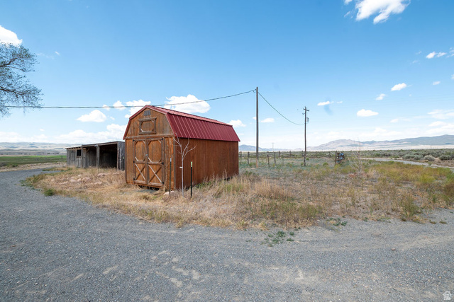 570 West Main Street Beaver, UT 84713 - Photo 38 of 43 Gravel driveway leading to a wood-sided outbuilding with a red metal roof