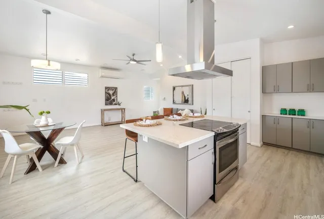 a kitchen with stainless steel appliances a stove a sink a dining table and chairs with wooden floor