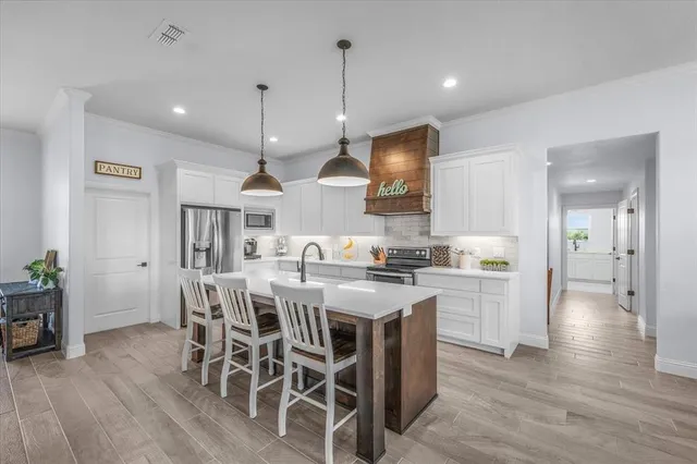 a kitchen with stainless steel appliances a dining table chairs stove and white cabinets