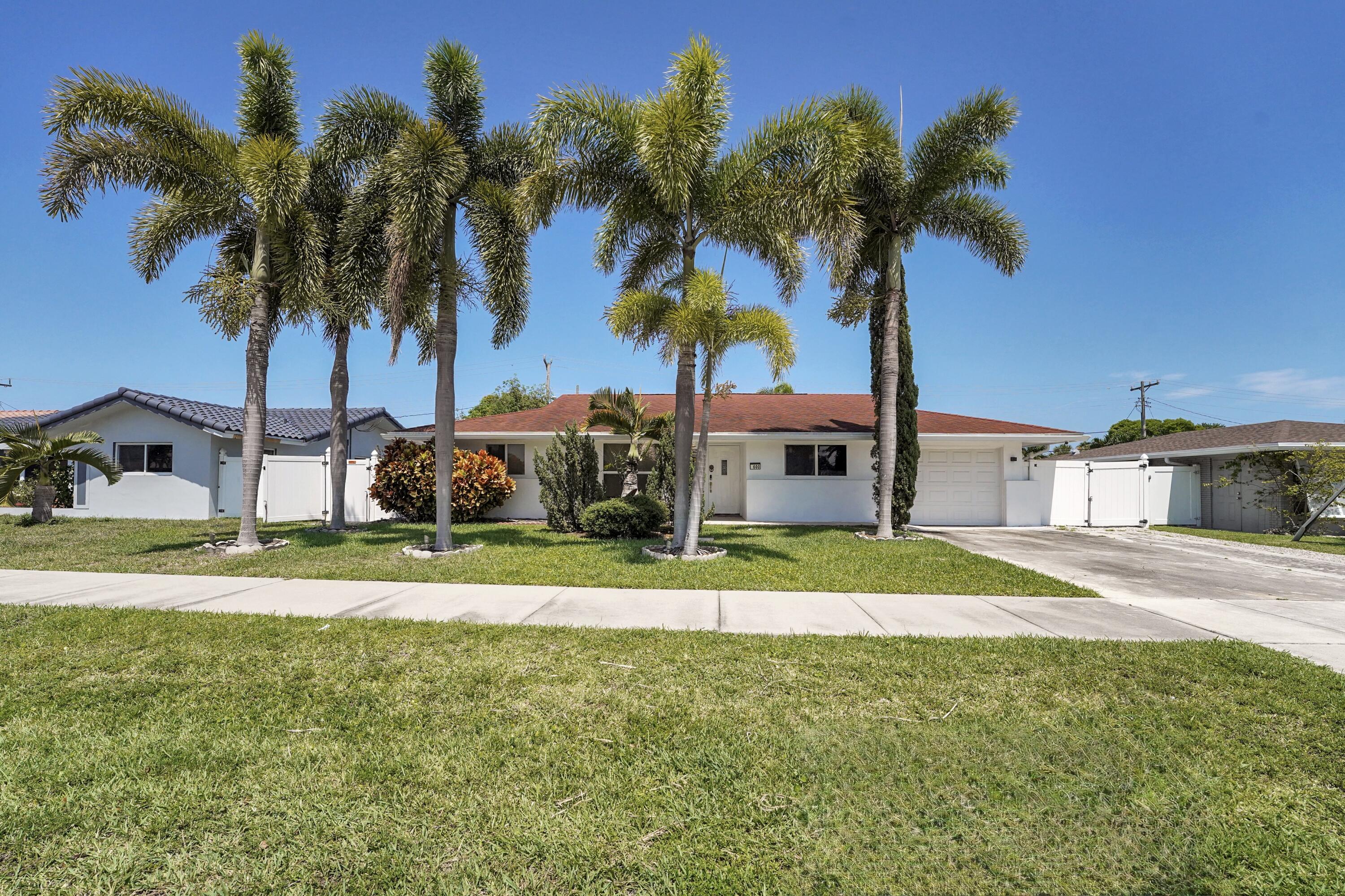 a view of a house with a yard and palm trees