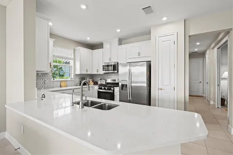 a kitchen with refrigerator a sink and white cabinets