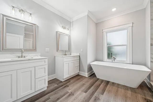 a spacious bathroom with double vanity sink a mirror a bathtub and window