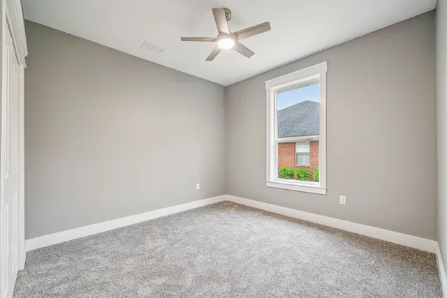 an empty room with windows and fan