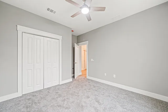 an empty room with closet and a chandelier fan