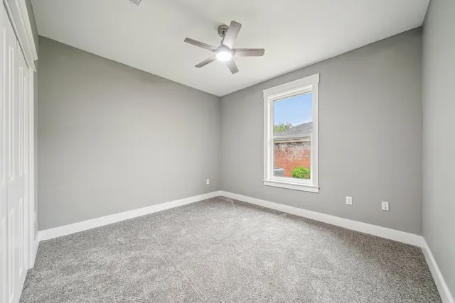 an empty room with windows and ceiling fan
