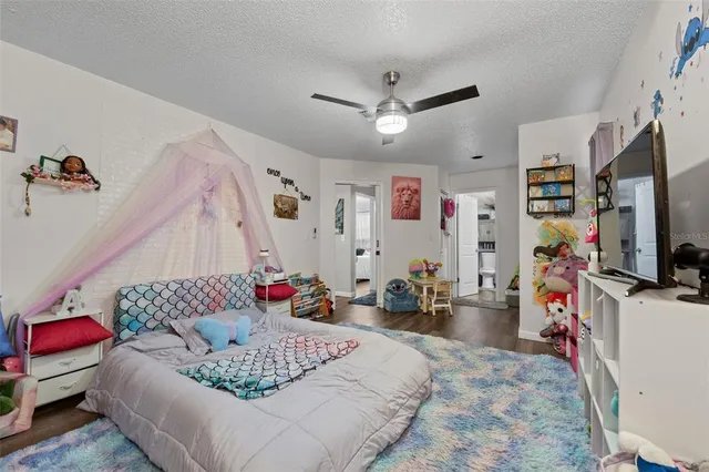 a bedroom with a bed a dresser and potted plant