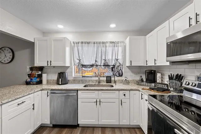 a kitchen with stainless steel appliances granite countertop a sink a stove and a refrigerator